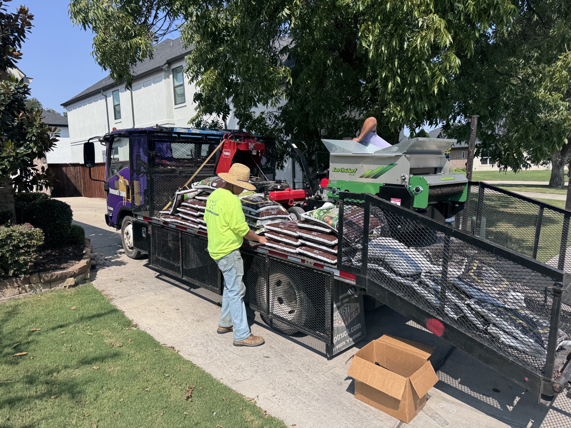 Denmark Lawn crew loading topdressing bags on the trailer with an EarthTurf unit
